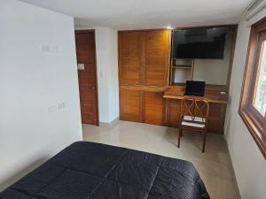 a bedroom with a bed and a desk with a television at Guest House with AC, close to Historical Centre 3 in Cartagena de Indias