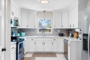 a white kitchen with white cabinets and a window at Escape by Beaches & Blue Angels in Pensacola