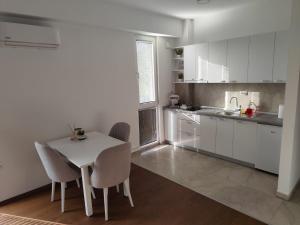 a white kitchen with a white table and chairs at Miha apartment-near Airport in Petrovec