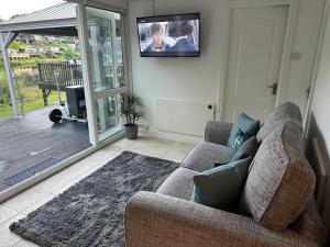 a living room with a couch and a flat screen tv at Swan lake lodge in Caernarfon
