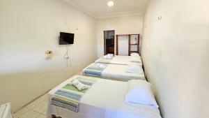 a row of three beds in a room at Toca da Ilha in Itarema