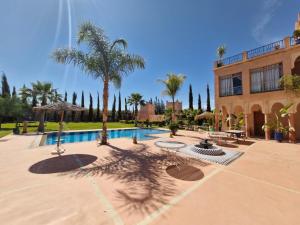 a courtyard with a pool with palm trees and a building at Les jardins d’ailleurs in Marrakech +49 photos