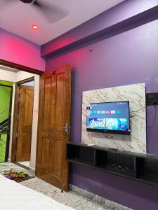 a room with a tv on a purple wall at Om Sai Ram Home Stay in Varanasi