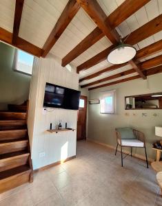 ein Wohnzimmer mit einem Flachbild-TV und einer Treppe in der Unterkunft Cabaña Amancay, comodidad y tranquilidad a pasos del centro - Ayres del Bosque Alojamientos in San Martín de los Andes