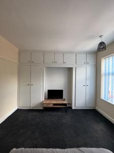 Una habitación vacía con armarios blancos y un televisor. en Serenity Rooms, en Leicester