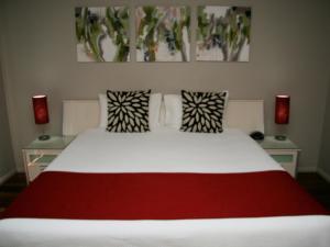 
a bed with a white comforter and pillows on it at Chaucer Palms Boutique B&B in Newcastle
