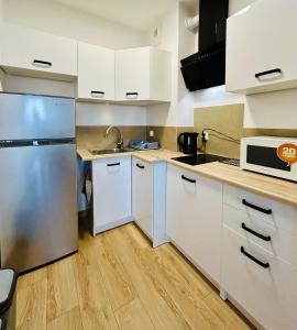 una cucina con armadi bianchi e frigorifero in acciaio inossidabile di Apartament the world a Władysławowo