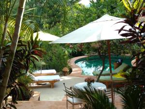a pool with an umbrella and chairs and a table at Casa d'Lobo Hotel Boutique in Malinalco