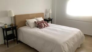 a white bed with two pillows on top of it at Faro Bay in Estepona