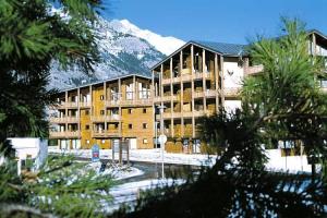 un grand bâtiment avec une montagne enneigée en arrière-plan dans l'établissement Résidence Les Balcons De La Vanoise - LES BALCONS DE LA VANOISE -BV410 MAE-6781, à Villarodin-Bourget