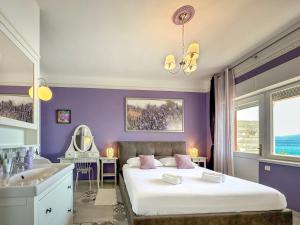 a bedroom with purple walls and a bed and a sink at Beach House Labineca in Gradac