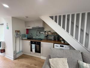 a kitchen with white cabinets and a white staircase at Gwens House - Traditional Cottage With Hot Tub in Brynsiencyn