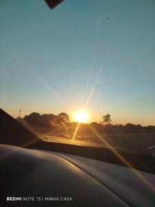 a view from a car window of the sun setting on a road at Pousada minha casa ouro verde in Botucatu
