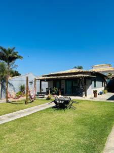 a house with chairs and a hammock in the grass at Geribá - casa plana, conforto, adaptada e tudo a pé in Búzios