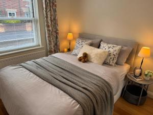 a teddy bear sitting on a bed in a bedroom at Riverside Folly Lodge Apartment, Oxford City Centre in Oxford