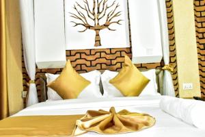 Una cama con almohadas amarillas y un cuadro de un árbol en la pared. en Mawimbi Jiko Hotel, en Taveta