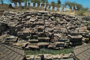 Un gran muro de piedra con un charco de agua. en Mawimbi Jiko Hotel, en Taveta