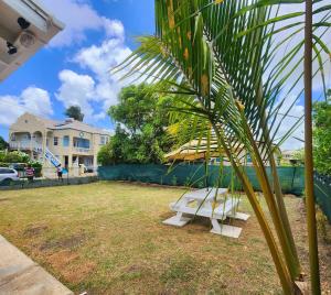 a white bench sitting in a yard next to a house at CoralStone Escape near beach and airport with private garden in Christ Church