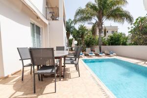 a patio with a table and chairs next to a swimming pool at Konnos Villa Ekaterina in Protaras