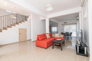 a living room with a red couch and a table at Konnos Villa Ekaterina in Protaras
