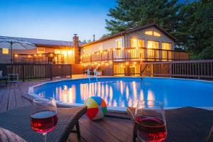a swimming pool with two glasses of wine and a house at NRG Retreat Pool, Games, Theater and Rock Walls in Fayetteville