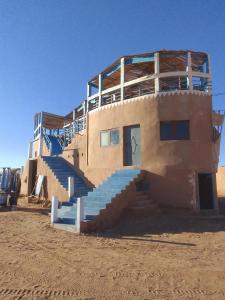 un edificio nel deserto con delle scale blu sopra di Titanic hôtel restaurant & désert excursions lac irik a Foum Zguid