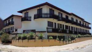 a large white building with black balconies at Aparthotel Praia do Pero in Cabo Frio
