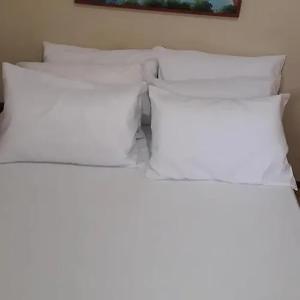 a group of four white pillows on a bed at Aparthotel Praia do Pero in Cabo Frio +7 photos