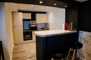 a kitchen with a black and white counter top at La Cachette Secrète - Maison romantique avec Balnéo et Sauna Privatif à Caen en Normandie in Caen +8 photos