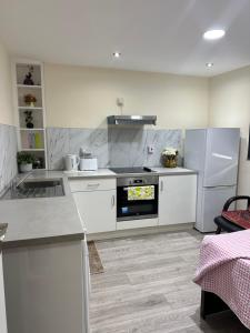 a kitchen with white cabinets and a stove and refrigerator at Room 3 - En-suite for 2 people in London