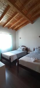 zwei Betten in einem Zimmer mit Holzdecken in der Unterkunft Casa de campo a 5 minutos da praia in Atouguio