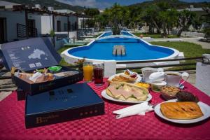 a table with breakfast foods and drinks and a pool at Petite Economy Lodge in Skiathos
