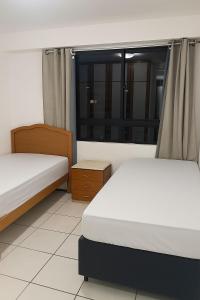 two beds in a room with a window at Alta Vista Apartamento - 1min da Praia de Iracema in Fortaleza +14 photos