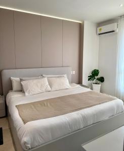 una camera da letto con un grande letto con lenzuola bianche e una pianta di Luxury Apartment betwen Cartagena and Barranquilla a Juan de Acosta Altre 35 foto