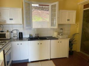 a kitchen with white cabinets and a window at Kafé House with breathtaking sea view in Deshaies