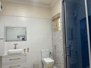 a bathroom with a toilet and a sink and a shower at Luxury 4 BR Apt w Parking, Hot tub, Magodo Estate in Magodo