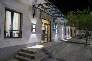 a building with stairs and windows and a tree at A e k a hotel Y V N in Yerevan