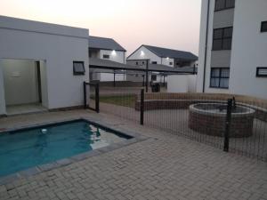a fence around a swimming pool in front of a building at Luna Luxury Living in Nelspruit