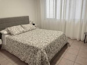 a bedroom with a bed with a blanket and a window at Puertoplaya 2 in Malpica +19 photos