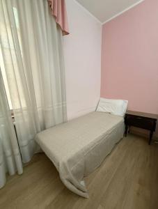 a small bed in a room with white curtains at Casa GILDA in Pisogne