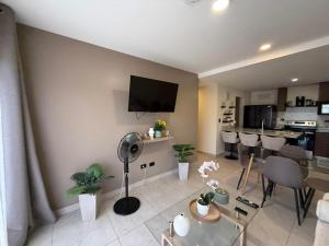 a living room with a tv and a table and chairs at Tropical Sunshine in Alajuela