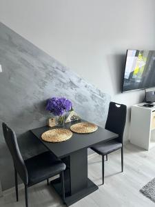 a black dining room table with two chairs and purple flowers at Luxusní apartmán v blízkosti centra města,Wifi, Netxlix in Hradec Králové