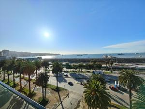 a view of a beach with palm trees and the ocean at Apartment with a view of the port of Valparaíso in Valparaíso