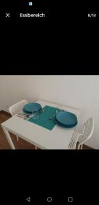 a white table with two blue plates on it at Suma Appartment 10min from Railstation in Koblenz +3 photos