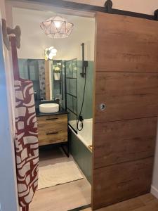 a bathroom with a wooden door with a sink and a tub at Petit Cocon des Rives Proche Stanislas-terrasse & parking gratuit in Nancy +47 photos