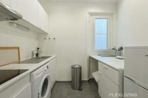 eine weiße Küche mit einem Waschbecken und einer Waschmaschine in der Unterkunft Cozy Room in Alésia Paris 14th in Paris