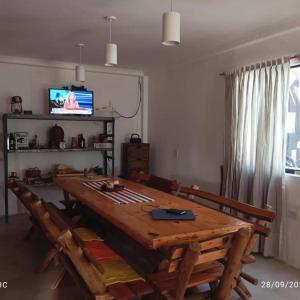 a dining room with a wooden table and a television at Casa Club Descanso in General Rodríguez