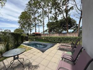 a patio with chairs and a table and a pool at Tropical Sunshine in Alajuela