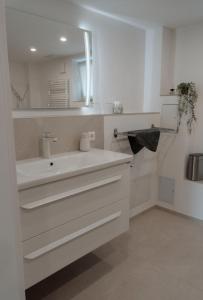 a white bathroom with a sink and a mirror at Ferienwohnung Traumblick in Bretzfeld