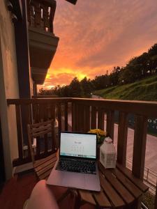 a laptop sitting on a bench on a balcony with a sunset at KTCH Holiday Home in Ulot